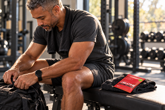 Man sitting on a gym bench beside a red ZYLO Creatine packet resting on a black towel.
