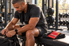 Man sitting on a gym bench beside a red ZYLO Creatine packet resting on a black towel.